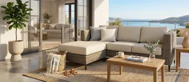 Cozy outdoor seating area with wicker sofa and ocean view.